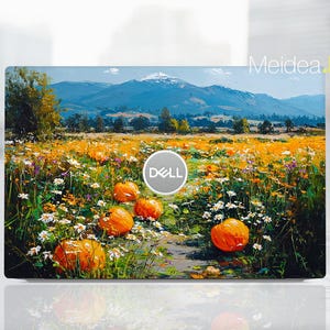 Puede incluir: Una funda para portátil con una pintura de paisaje. La obra de arte representa un campo de calabazas naranjas y flores silvestres, con montañas al fondo. El logotipo de Dell es visible. Las palabras "Meidea Han" también son visibles.