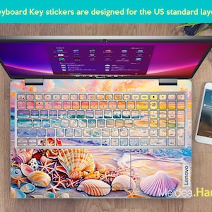 Op de afbeelding: Een laptop-toetsenbord met een kleurrijke sticker met een schelpdesign. De sticker toont verschillende schelpen, zeesterren en zand. Het toetsenbord is gelabeld met "Lenovo".