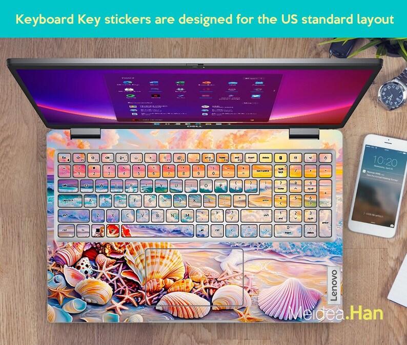 Op de afbeelding: Een laptop-toetsenbord met een kleurrijke sticker met een schelpdesign. De sticker toont verschillende schelpen, zeesterren en zand. Het toetsenbord is gelabeld met "Lenovo".
