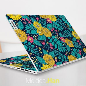 May include: A white laptop with a floral design on the lid. The design features yellow, pink, and teal flowers on a dark blue background. The laptop has the Lenovo logo on the lid.
