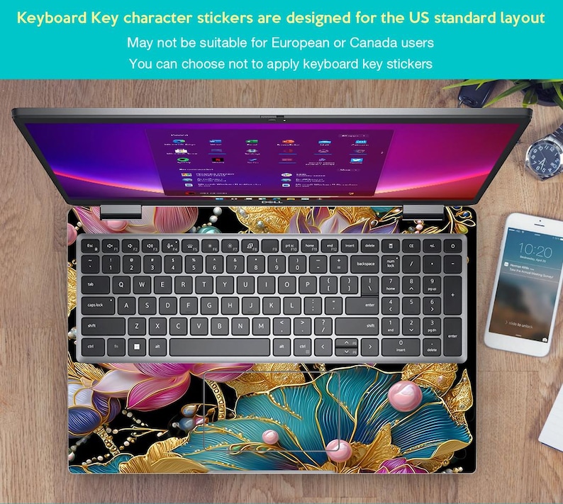 May include: Laptop with a floral design keyboard skin. The skin features gold, teal, pink, and black colors. The keyboard has standard US layout keys. The screen displays a colorful interface. A smartphone and watch are also visible.
