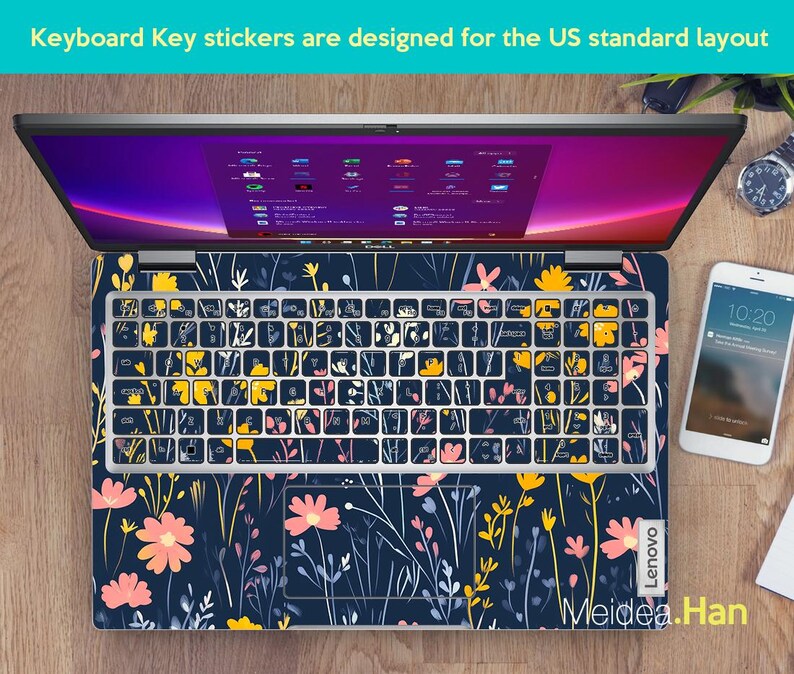 May include: A laptop computer with a floral keyboard sticker. The sticker features a dark blue background with pink, yellow, and white flowers and stems. The laptop is a Lenovo.
