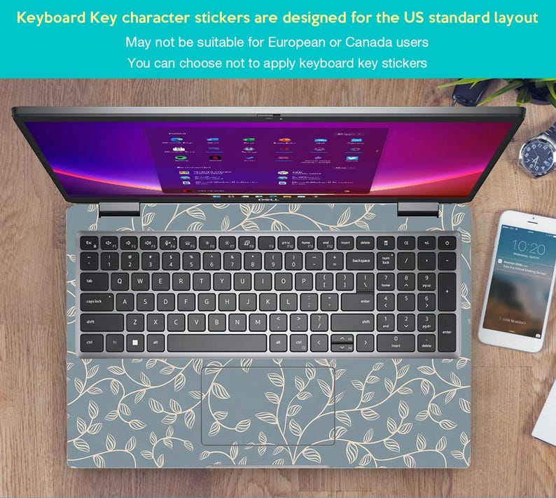 May include: Laptop with a keyboard skin featuring a light blue background and a white leaf pattern. The laptop screen displays a colorful interface. A smartphone and a watch are visible on the wooden surface. Text on the image states: "Keyboard Key character stickers are designed for the US standard layout."