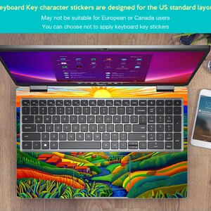 May include: A laptop computer with a colourful landscape design keyboard sticker. The sticker features a green river, yellow hills, and green trees. The laptop screen is on and shows a desktop with multiple icons. The text on the sticker reads "Keyboard Key character stickers are designed for the US standard layout. May not be suitable for European or Canada users. You can choose not to apply keyboard key stickers."