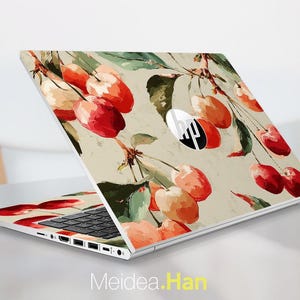 May include: A laptop with a custom skin featuring a watercolor design of cherries and leaves in shades of red, orange, and green against a beige background. The laptop is open, displaying the keyboard and the HP logo. The text "Meidea.Han" is visible at the bottom.