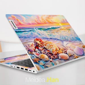 Op de afbeelding: Een laptop met een kleurrijk schelpdesign op de deksel. Het ontwerp toont een zonsondergang boven de oceaan met golven die op de kust breken. De laptop is open en het toetsenbord is zichtbaar. Het Lenovo-logo is zichtbaar op de deksel.