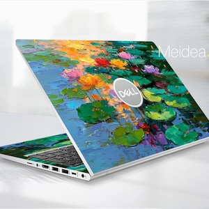 May include: A Dell laptop with a vibrant floral design featuring pink, orange, and purple flowers, and green lily pads on a blue water background. The laptop is open, displaying the keyboard and ports. The Dell logo is visible.