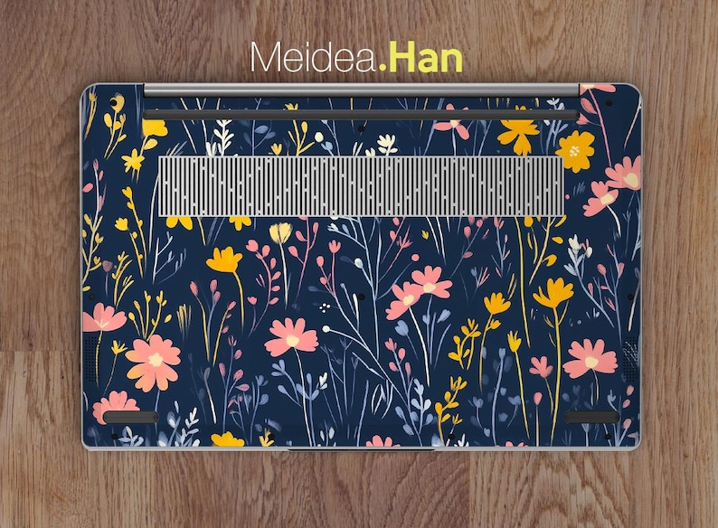 May include: A laptop skin with a floral pattern. The design features pink and yellow flowers on a dark blue background.