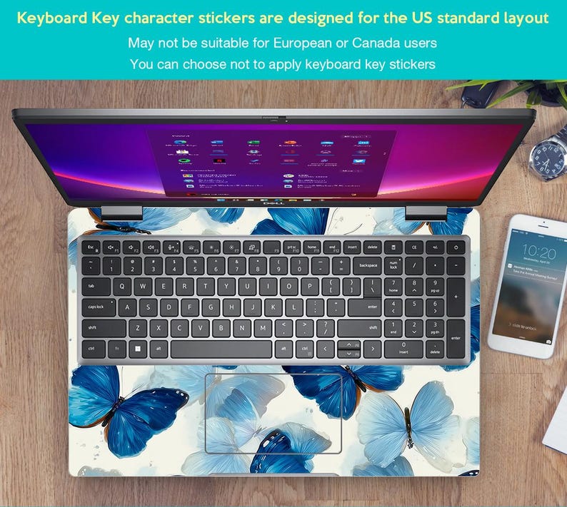 May include: Laptop with a keyboard skin featuring a blue butterfly design. The keyboard has a standard US layout. The screen displays a colorful interface. A smartphone and watch are visible on the wooden surface.