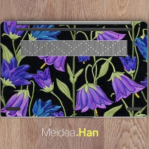 May include: Laptop skin featuring a floral design with purple and blue bellflowers on a black background. The flowers have green stems and leaves. The text "Meidea.Han" is at the bottom.
