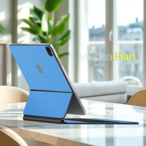 Könnte beinhalten: Eine blaue Tablet-Hülle mit strukturiertem Muster und integrierter Tastatur. Die Hülle ist geöffnet und zeigt den Bildschirm des Tablets und das Apple-Logo. Der Text "Meidea.Han" ist im Hintergrund sichtbar.