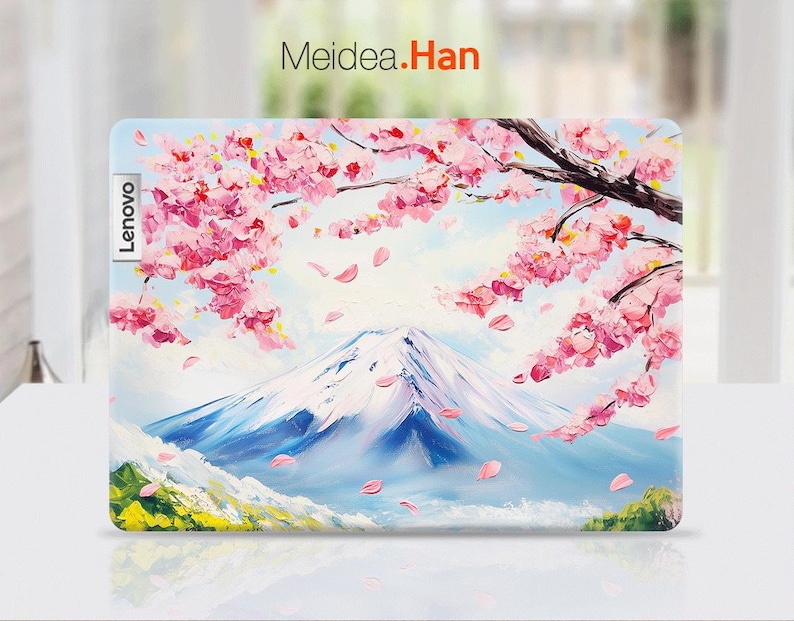May include: A laptop skin featuring a colorful painting of a mountain range with pink cherry blossoms in the foreground. The text "Lenovo" is printed on the left side of the skin and "Meidea.Han" is printed at the top.