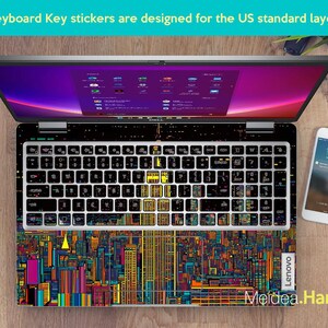 Pode incluir: Um teclado de laptop com adesivos coloridos de um horizonte urbano. Os adesivos s&atilde;o projetados para um teclado padr&atilde;o americano. O texto "Lenovo" e "Meldea.Han" s&atilde;o vis&iacute;veis no laptop.