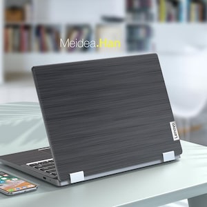 May include: A closed black laptop computer with a brushed metal finish and the Lenovo logo on the lid. The laptop is sitting on a light blue table.