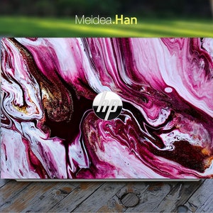 May include: A laptop computer with a pink, white and gold marbled design. The laptop has an HP logo on the lid.