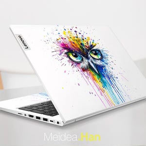 Pu&ograve; includere: Laptop bianco con un colorato design a gufo ad acquerello. L'opera d'arte presenta gli occhi di un gufo e uno spruzzo di colori arcobaleno. Il laptop ha una tastiera nera e il logo Lenovo.