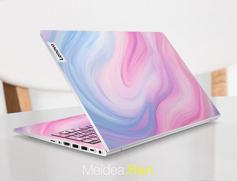 May include: A white laptop with a pink and blue marbled design on the lid. The Lenovo logo is visible on the lid. The laptop is open and the keyboard is visible.