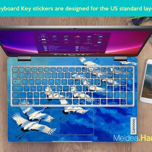 May include: Laptop keyboard with blue key stickers featuring white cranes against a blue sky design. The keyboard keys are light blue. The text "Keyboard Key stickers are designed for the US standard layout" is at the top. The brand name "Lenovo" is visible.