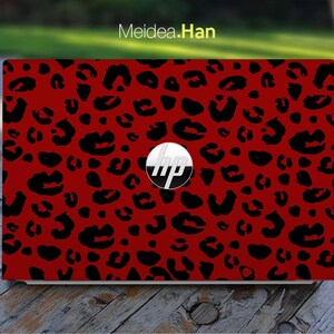 Könnte beinhalten: Eine rote Laptop-Haut mit einem schwarzen Leopardenmuster. Das HP-Logo ist auf der Haut sichtbar.