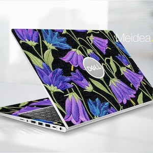 May include: A Dell laptop with a floral design. The laptop's lid and palm rest are covered in a black fabric with embroidered-style purple and blue bellflowers and green leaves. The Dell logo is visible on the lid. The text "Meidea.Han" is in the upper right corner.