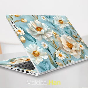 Puede incluir: Un port&aacute;til blanco con un dise&ntilde;o floral azul y blanco en la tapa. El dise&ntilde;o presenta grandes flores blancas con centros amarillos y flores blancas m&aacute;s peque&ntilde;as con centros amarillos. El port&aacute;til est&aacute; abierto y el teclado es visible.