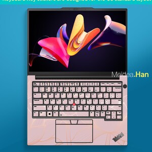 May include: A pink laptop with a floral design on the keyboard and palm rest. The screen displays a colorful abstract image. The keyboard has key stickers. Text on the screen says "Keyboard Key stickers are designed for the US standard layout".