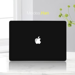 May include: A black laptop computer with a white Apple logo on the lid. The laptop is sitting on a white surface.