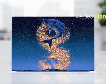 May include: A rectangular laptop skin featuring a dark blue night sky filled with stars. A large blue whale leaps above a white lighthouse, surrounded by a swirling trail of glowing yellow and orange light particles that form an S-shaped pattern.