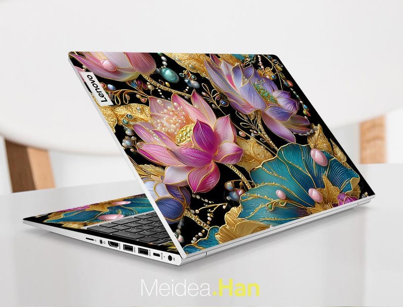 May include: A Lenovo laptop with a floral design. The laptop features a black background with gold, teal, pink, and purple flowers. The laptop is open, displaying the keyboard and screen. The text "Meidea Han" is at the bottom of the image.