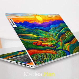 May include: A laptop computer with a colourful landscape design on the lid. The design features a sunset, mountains, and a river. The laptop is open and the keyboard is visible. The Lenovo logo is visible on the lid.