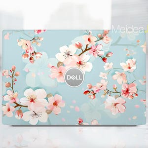 May include: A light blue laptop skin featuring a floral design with pink and white blossoms and green stems. The Dell logo is centered on the skin. The text "Meidea Han" is in the upper right corner.