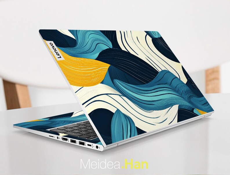May include: A laptop computer with a blue, yellow, and white abstract design on the lid. The Lenovo logo is visible on the lid.