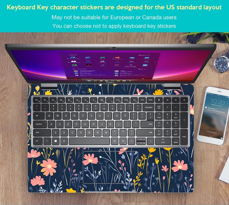 May include: A silver laptop computer with a floral design keyboard sticker. The laptop is open and the screen is displaying a desktop with multiple icons. The laptop is sitting on a wooden surface with a white smartphone and a watch.