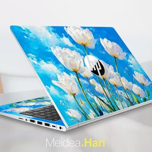 May include: A laptop with a floral design featuring white flowers against a bright blue sky. The laptop has a black keyboard and the HP logo. The design extends across the lid and the keyboard area. The text "Meidea.Han" is at the bottom.