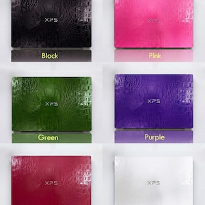 May include: A collection of laptop computers in various colors, including black, pink, green, purple, red, and white. Each laptop has a textured surface and the text "XPS" on the top. The colors are labeled below each laptop.