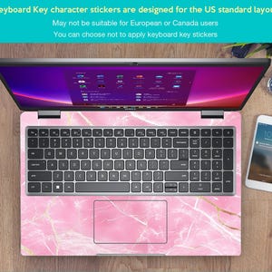 May include: A laptop computer with a pink marble design keyboard sticker. The sticker features a pink and white marble pattern with gold accents. The laptop screen is displaying a desktop with multiple icons.