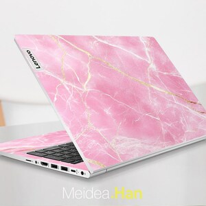 May include: A pink and gold marble laptop skin with the word "Lenovo" printed on the left side.