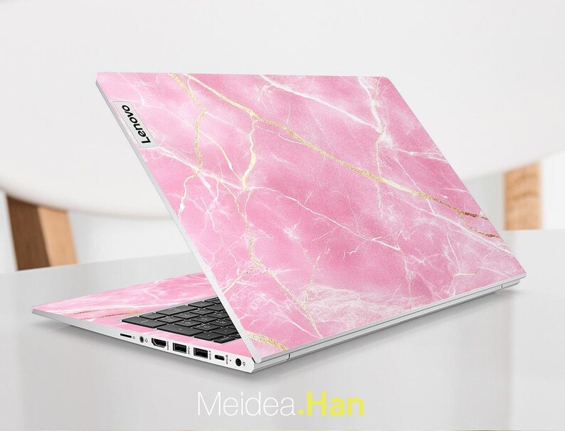 May include: A pink and gold marble laptop skin with the word "Lenovo" printed on the left side.