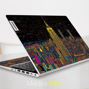 Pode incluir: Um laptop prateado com um design de cidade colorida na tampa. O design apresenta um pr&eacute;dio alto com um fundo preto e linhas coloridas. O laptop tem um teclado preto e um touchpad prateado. O logotipo da Lenovo &eacute; vis&iacute;vel na tampa.