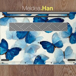 May include: Laptop skin featuring a watercolor design of blue butterflies on a white background. The butterflies vary in shades of blue, with some appearing lighter and more translucent. The text "Meidea.Han" is visible at the top.