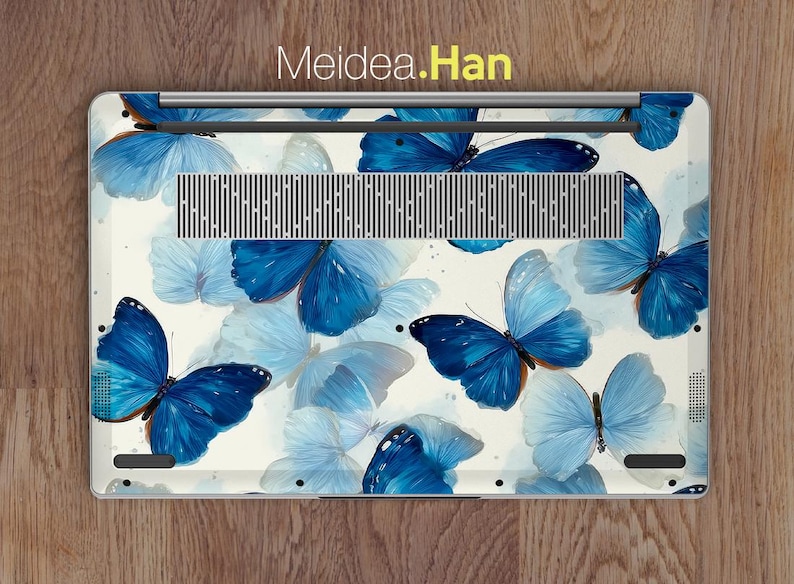 May include: Laptop skin featuring a watercolor design of blue butterflies on a white background. The butterflies vary in shades of blue, with some appearing lighter and more translucent. The text "Meidea.Han" is visible at the top.