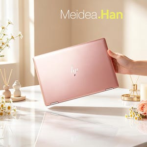 Może przedstawiać: Różowo-złoty laptop HP jest trzymany pod kątem, pokazując logo HP. Laptop znajduje się na białej marmurowej powierzchni, z kwiatami i elementami dekoracyjnymi w tle. Tekst "Meidea.Han" jest wyświetlany u góry.