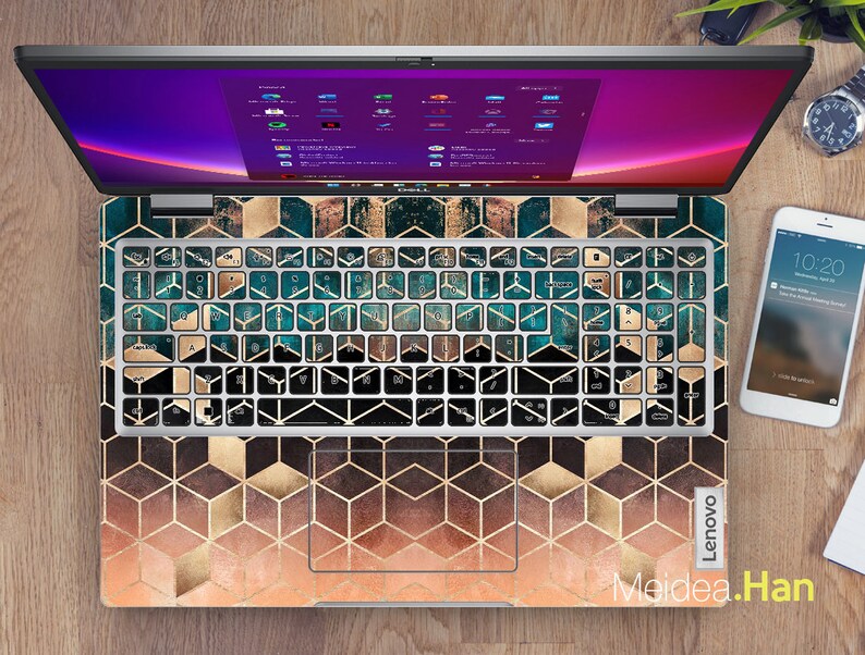 May include: A laptop computer with a geometric pattern keyboard cover in shades of gold, teal, and brown. The cover features a repeating pattern of hexagons and squares. The laptop screen is displaying a desktop with multiple icons.