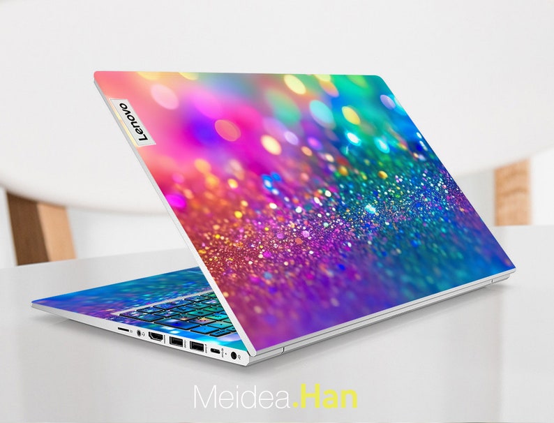 May include: A laptop computer with a colorful glitter design on the lid. The design features a rainbow of colors, including pink, purple, blue, green, and yellow. The Lenovo logo is visible on the lid.