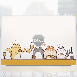 May include: A white laptop with a yellow and white design featuring a group of cartoon cats. The cats are sitting at a table with food and drinks. The laptop has a Dell logo on the front.