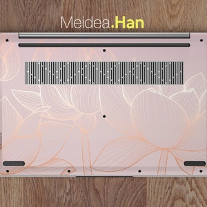 Puede incluir: Una funda para port&aacute;til con un fondo rosa claro y un dise&ntilde;o floral dorado. La funda cubre la parte inferior del port&aacute;til e incluye el texto "Meidea.Han" en la parte superior. El dise&ntilde;o floral es un delicado dibujo lineal de flores de loto.