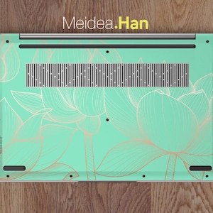May include: A laptop computer with a mint green and gold floral design on the back. The design features delicate, stylized lotus flowers.