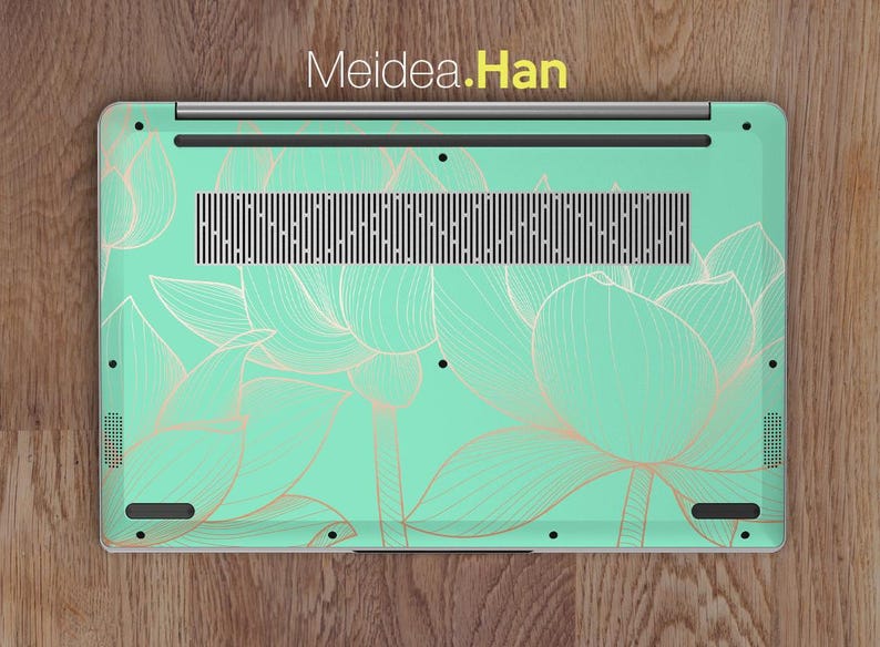 May include: A laptop computer with a mint green and gold floral design on the back. The design features delicate, stylized lotus flowers.