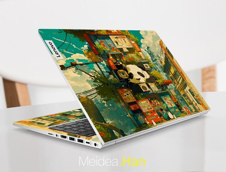 K&ouml;nnte beinhalten: Ein Laptop mit einem farbenfrohen, illustrierten Design, das einen Pandab&auml;ren und eine Stadtlandschaft zeigt. Das Design umfasst Geb&auml;ude, Verkaufsautomaten und eine Stra&szlig;enszene. Der Laptop hat eine schwarze Tastatur und ein silbernes Geh&auml;use. Das Lenovo-Logo ist auf der R&uuml;ckseite des Laptops sichtbar.