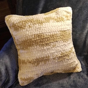 May include: A white and beige striped throw pillow with a soft, fluffy texture. The pillow is sitting on a blue armchair.